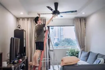 Pria membersihkan kipas langit-langit di rumah