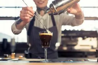 Vrouw die koffiecocktail maakt bij cafébalie