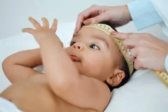 Klinikte bir bebeğin kafasını ölçen bir çocuk doktorunun çekimi