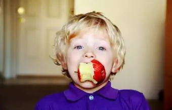 Dječak jede crvenu jabuku