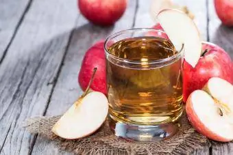 አዲስ በተቆረጡ ፖም የተከበበ የፖም cider ብርጭቆ