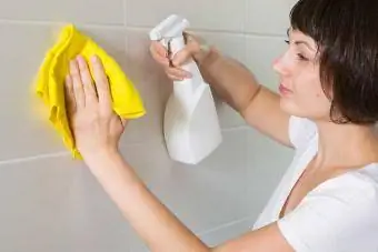 wanita membersihkan grout di bilik mandi