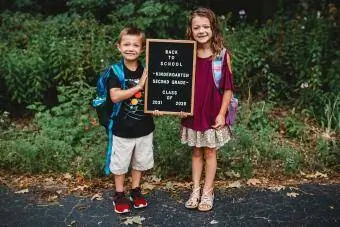 brolis ir sesuo laiko pirmos mokyklos dienos ženklą