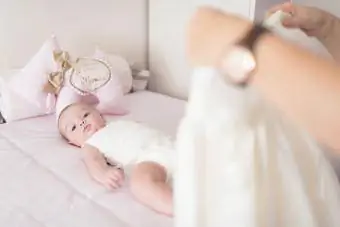 Mutter kleidet Baby im heimischen Schlafzimmer ein