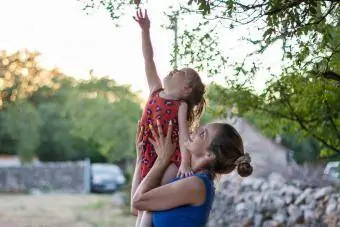 madre che aiuta la figlia a raggiungere il ramo dell'albero