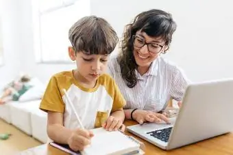 ילד עושה שיעורי בית בזמן שאמא עובדת