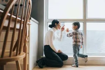 Mère et fils parlant ensemble près de la grande fenêtre de l'appartement