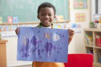 Menino segurando pintura na aula de arte