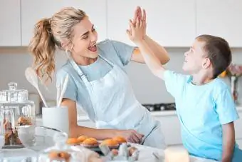 Glad mamma som ger sin son en high five i köket