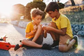 gutt hjelper venn med å binde kneet