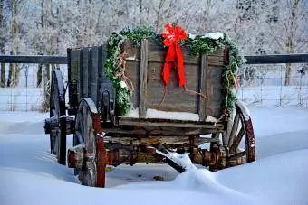 Carrinho de madeira antiquado com decorações de Natal na neve