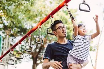 ayah membantu putrinya dengan bar monyet taman bermain