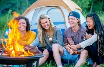 teenageři sedí u táboráku