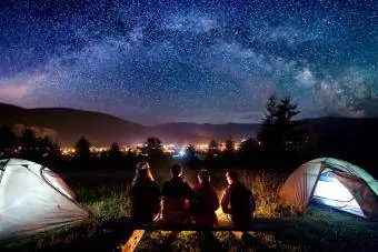 Kamp ve çadırların yanında yıldızları izleyen aile