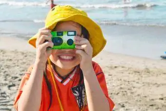 Mädchen fotografiert mit Einwegkamera am Strand