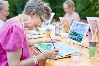Ältere Frau lächelt, während sie mit der Gruppe zeichnet
