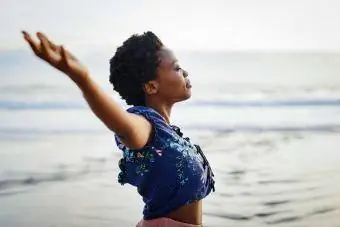 γυναίκα με τα χέρια τεντωμένα νιώθοντας ελεύθερη στην παραλία