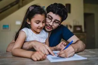 Homem assinando papéis com a filha no colo