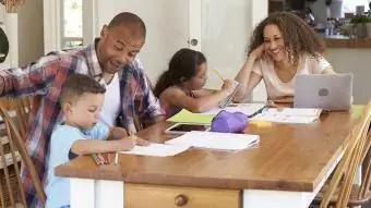 Vecāki palīdz bērniem pildīt mājas darbus pie galda