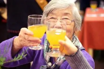 Senior Asian Woman Raising Glass of Non-Alcoholic Punch for Toast