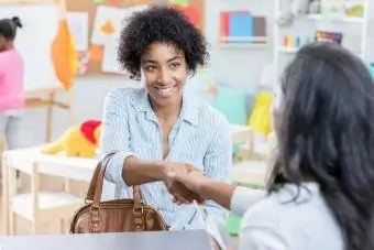 Jonge moeder schudt de hand tijdens het interview op de kinderopvang