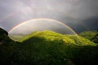 Arco-íris duplo sobre paisagem ondulada
