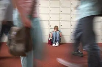 Okul koridorunda dolapların yanında oturan genç kız