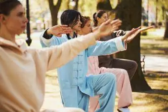 Tai chi dersi sırasında tek ayak üzerinde duran kadınlar