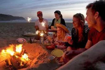 amigos acendendo faíscas na fogueira na praia