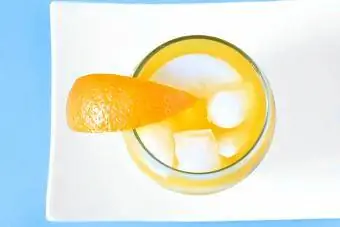 Overhead na imahe ng isang baso ng orange juice na may yelo at orange wedge