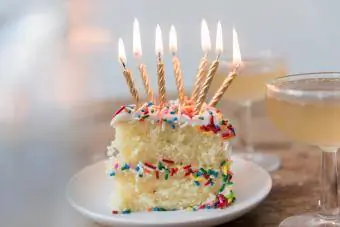 Kaarsen branden op een plakje cake met hagelslag in de buurt van champagne