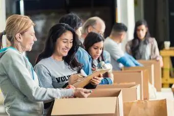 Različiti odrasli pakuju kutije za donacije u dobrotvornoj banci hrane