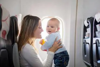 Jauna mamma spēlē savu mazuli uz lidmašīnas klāja