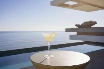 Koktajl w szklance martini na słonecznym, luksusowym patio z widokiem na ocean