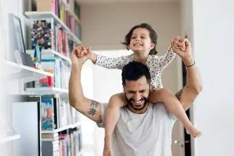 Šťastný otec nesie dievča na ramene