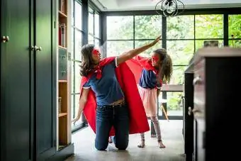 Flicka med mamma i röd superhjältedräkt hemma