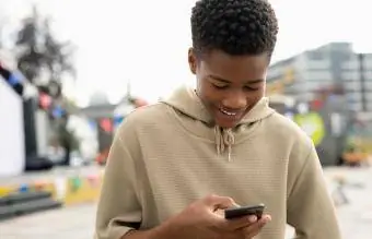 Uśmiechnięty nastolatek wysyłający SMS-y