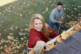 Пара убирает листья возле своего дома