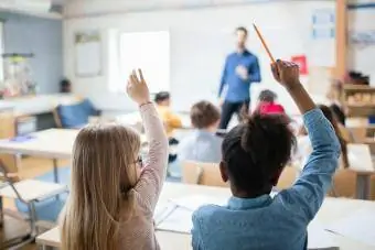 Studenter som sitter med händerna upp i klassrummet