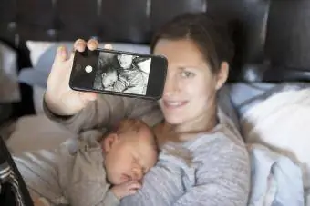 Babymeisje slaapt op moeders borst, terwijl moeder selfie maakt