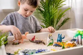 Dinozorlarla duyusal çöp kutusuyla oynayan çocuk