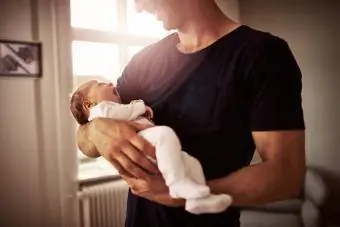 پدری جدید که نوزادی را در آغوش گرفته است که از محل کار خود مرخصی می گیرد