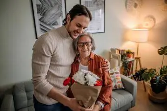 Hijo en visita a su madre, regalándole flores.