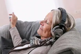 Wanita senior mendengarkan musik dengan headphone