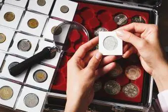 Scatola con monete da collezione e lente d'ingrandimento