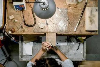 Nhìn từ trên cao của nữ thợ kim hoàn đang sử dụng cưa đối phó tại bàn làm việc