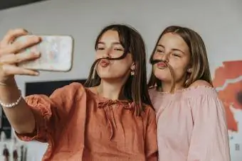Freunde machen falschen Schnurrbart mit Haaren, während sie zu Hause ein Selfie machen