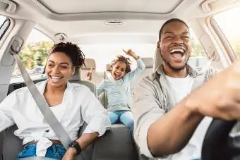 Familia feliz de tres cantando divirtiéndose montando coche