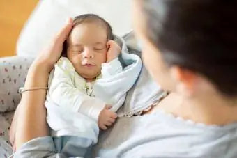 annesinin kollarında uyuyan bebek müzik dinliyor