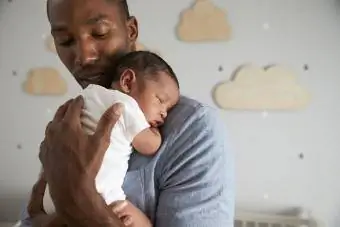 oče drži spečega dojenčka